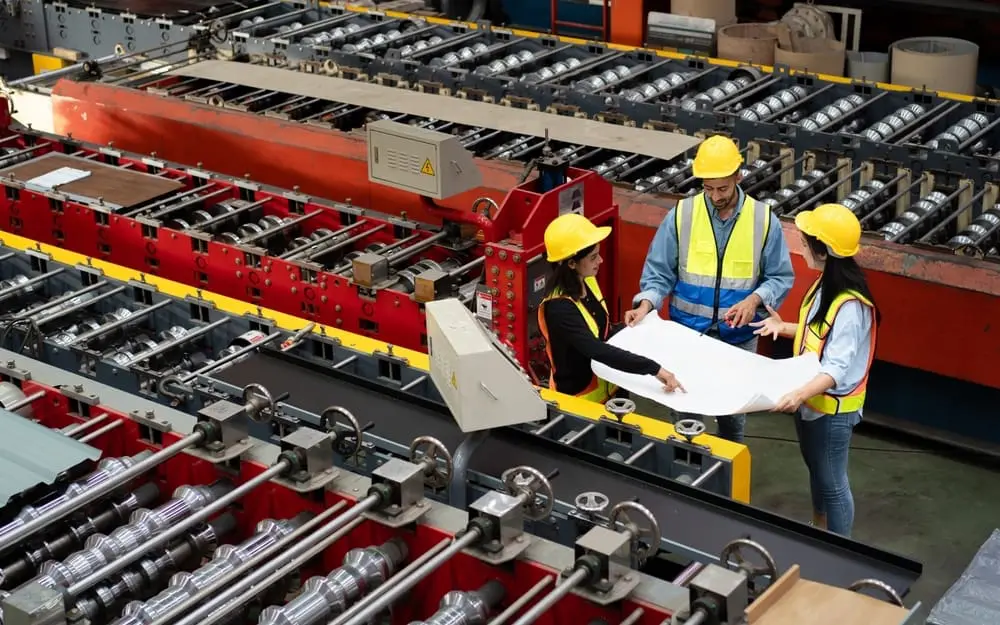 Workers inspecting conveyor belt machine in factory