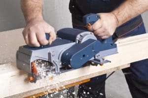 wood planing machine in use by a woodworker